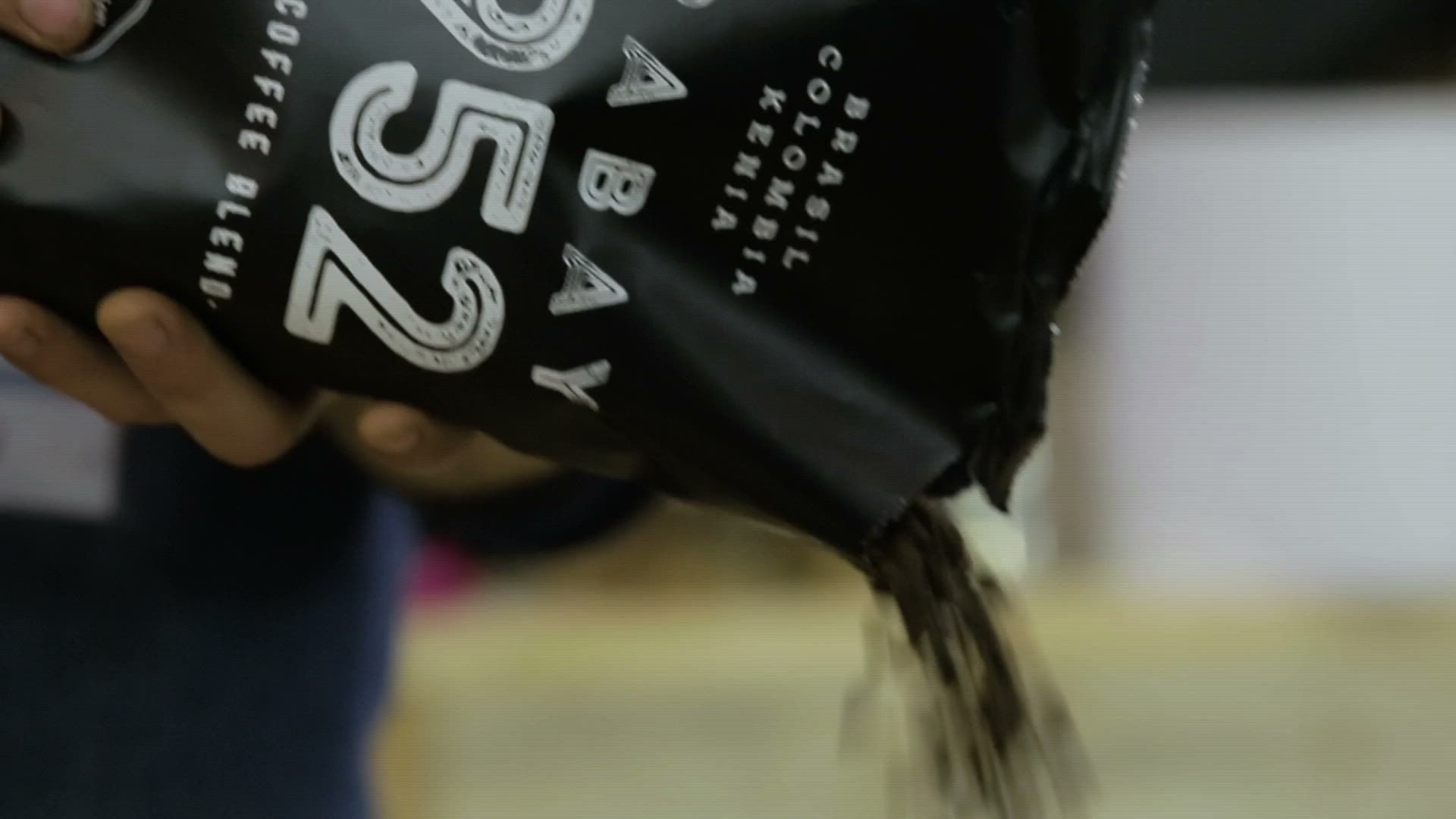 Una persona saca granos de café de una máquina.